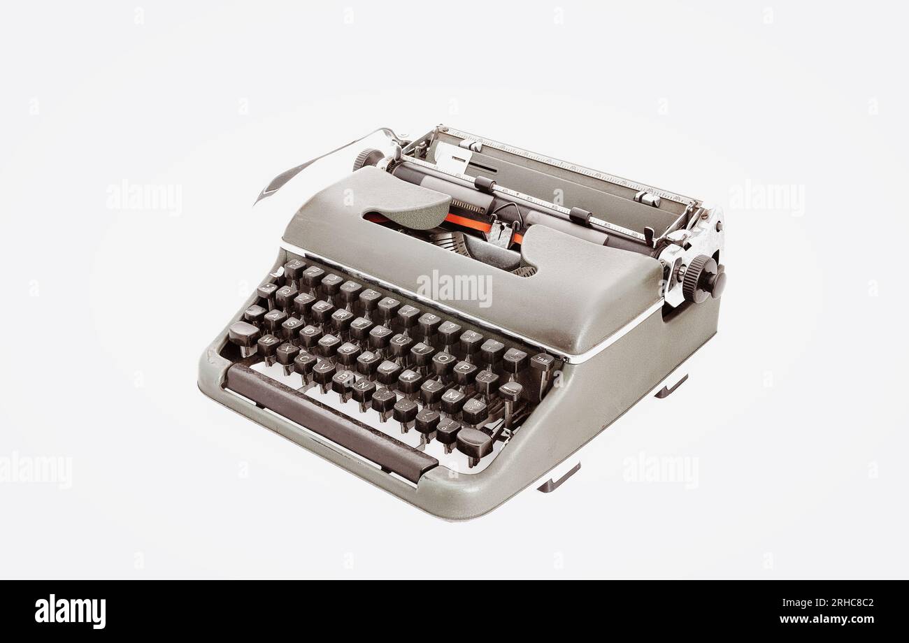Metal typewriter reminiscent of bygone days with dark keys and an iconic lever. Photographed from above at a three-quarters angle, starkly offset by w Stock Photo