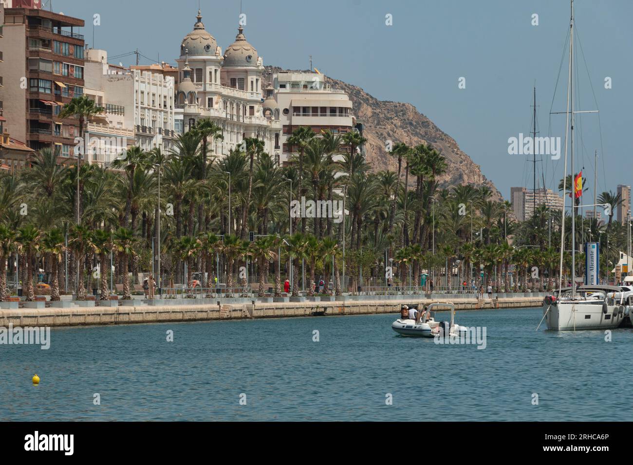 View of the palm trees and Casa Carbonell in Alicante, Spain. There are boats and an inflatable boat sailing. Tuesday, August 15, 2023 at 13:00pm. GPS Stock Photo