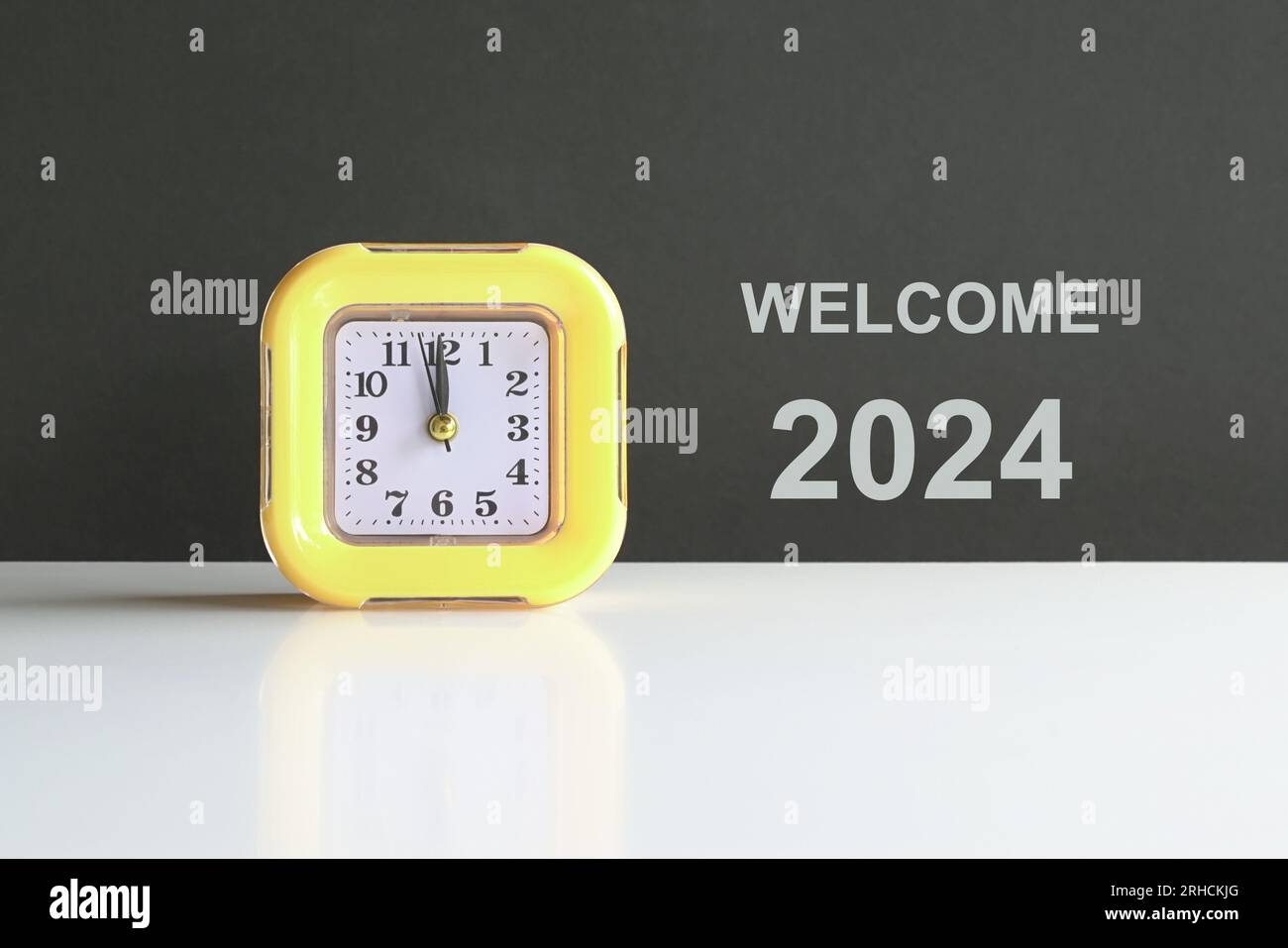 Welcome 2024, next to a yellow clock. Happy New Year concept. Stock Photo