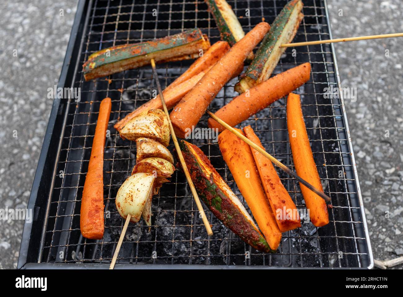 Grill with vegetable skewers seasoned carrots, zucchini, and onions