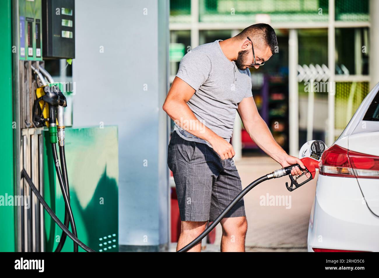 Young man refueling car gas tank with gasoline. Confident driver