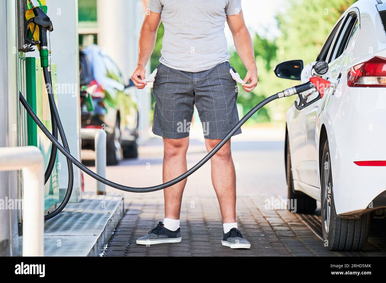 Man left with empty pockets after spending all money on fuel. Cropped view of man showing that he has no money after refueling his car. High fuel prices concept. Stock Photo