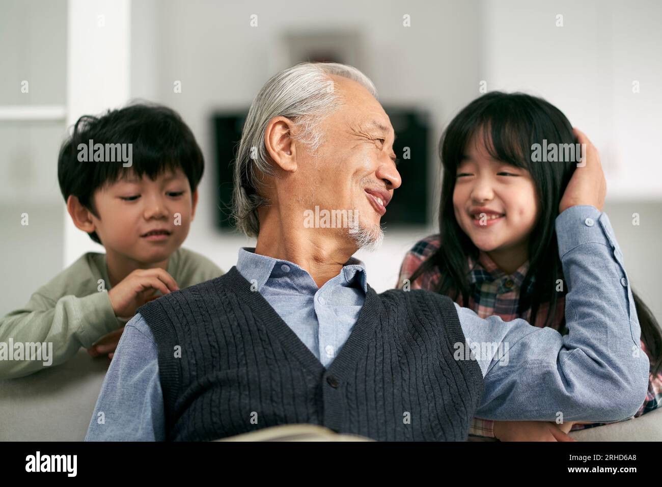 senior asian grandfather having a good time with two grandchildren at home Stock Photo