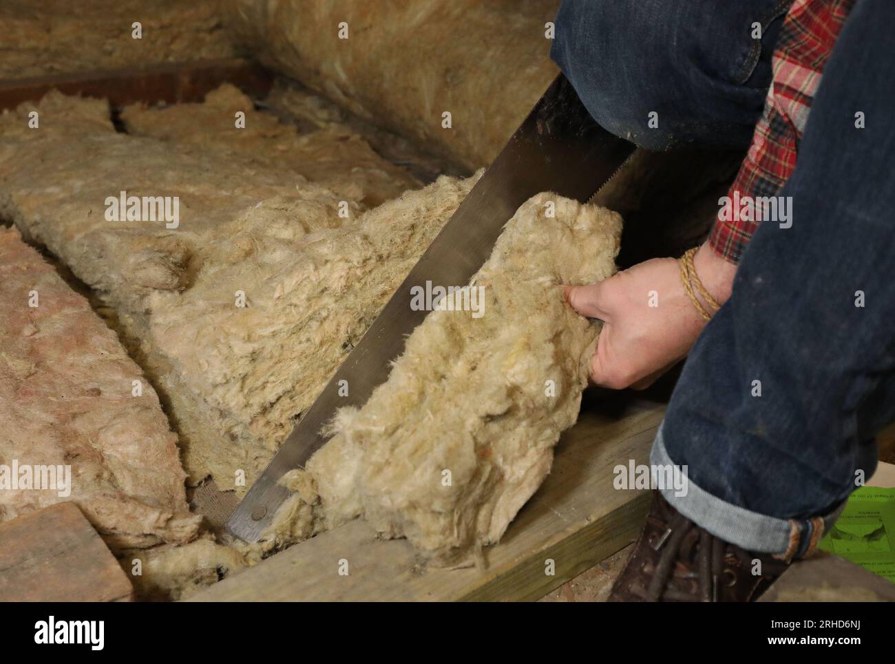 File photo dated 14/11/17 of a person laying loft insulation. Trading Standards Scotland is launching a new campaign to help people avoid scams linked to energy-efficiency measures and point them towards trusted sources of advice. The campaign comes as reports of online adverts, cold callers and rogue traders offering misleading information about the availability of grants and funding for energy-efficient schemes continue to climb. Dishonest companies are known to tell householders they are eligible to receive government or council funding for products such as insulation, boilers and heating s Stock Photo