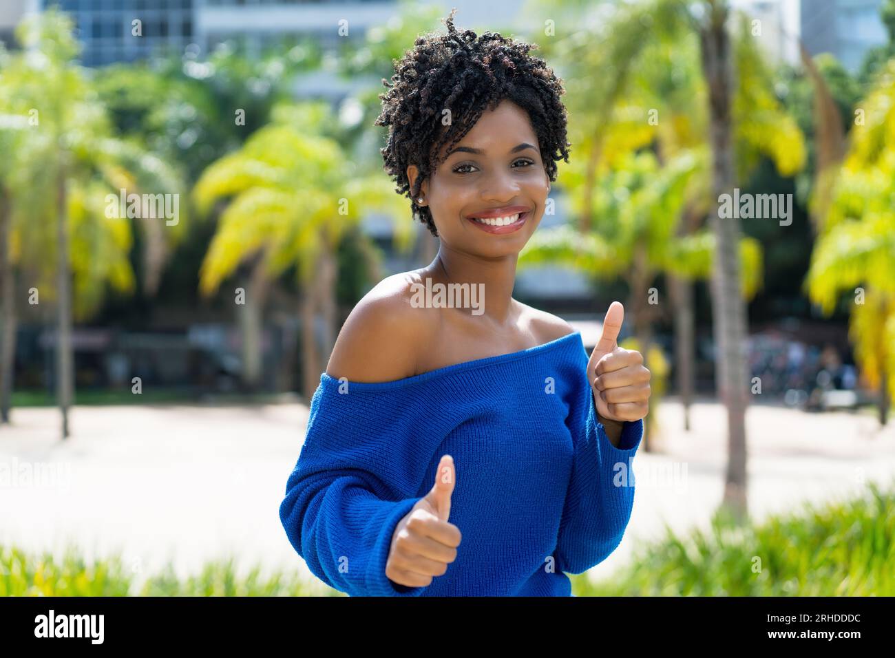 Happy african american young adult woman with curly hair outdoor with ...