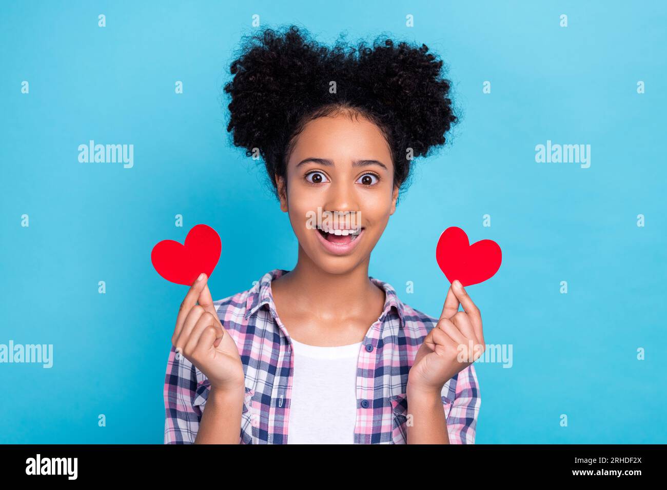 Photo of shiny pretty lady wear plaid shirt open mouth holding two little heart cards isolated blue color background Stock Photo