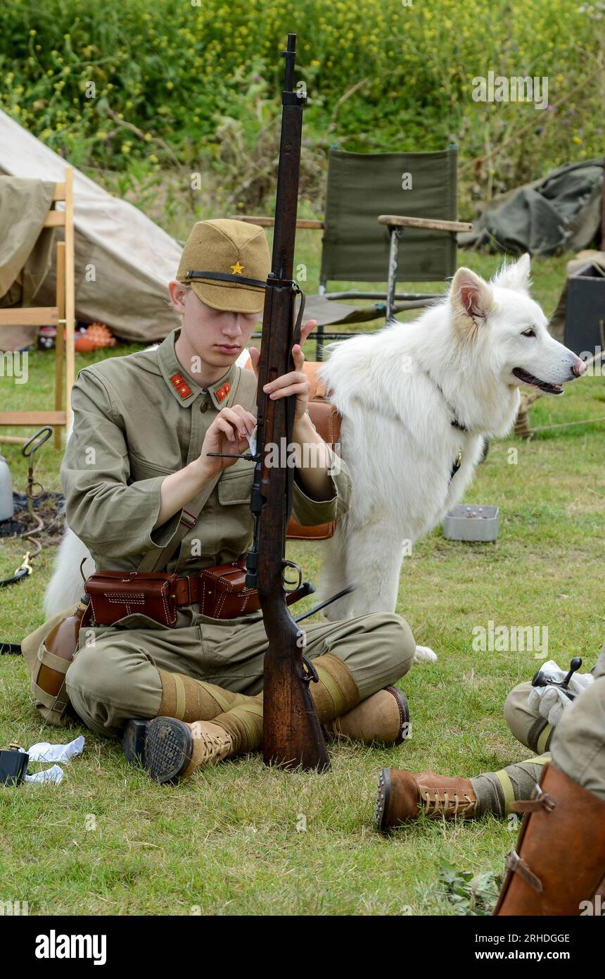 WWII Imperial Japanese Army re-enactor soldier, cleaning gun with dog at re-enactment event at Damyns Hall, Essex, UK Stock Photo