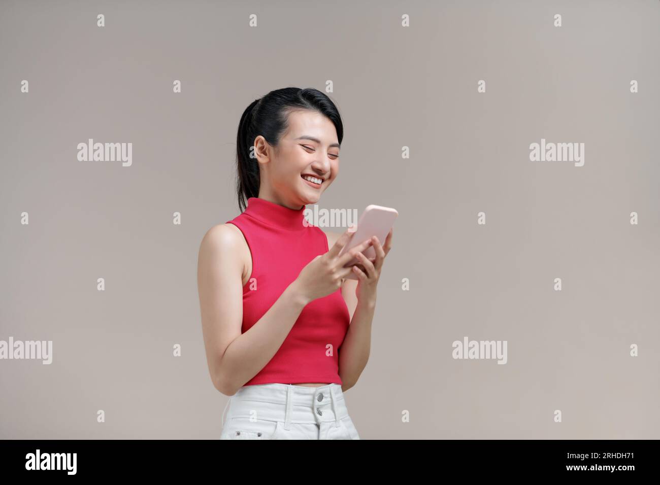 sexy Asian woman play game online on smartphone and smile Stock Photo