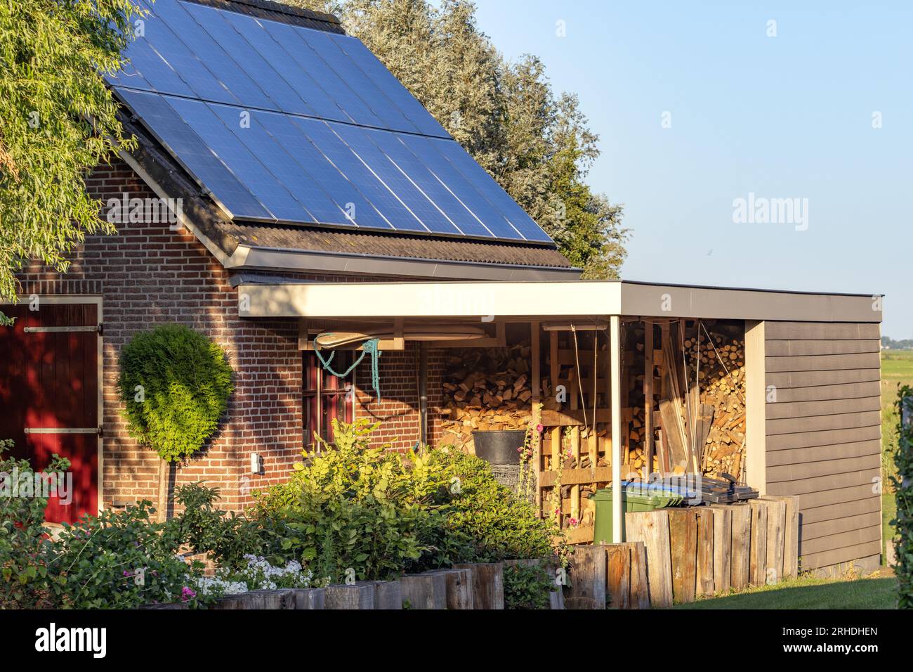 detached house with solar panels on the roof and firewood in the carport Stock Photo Alamy