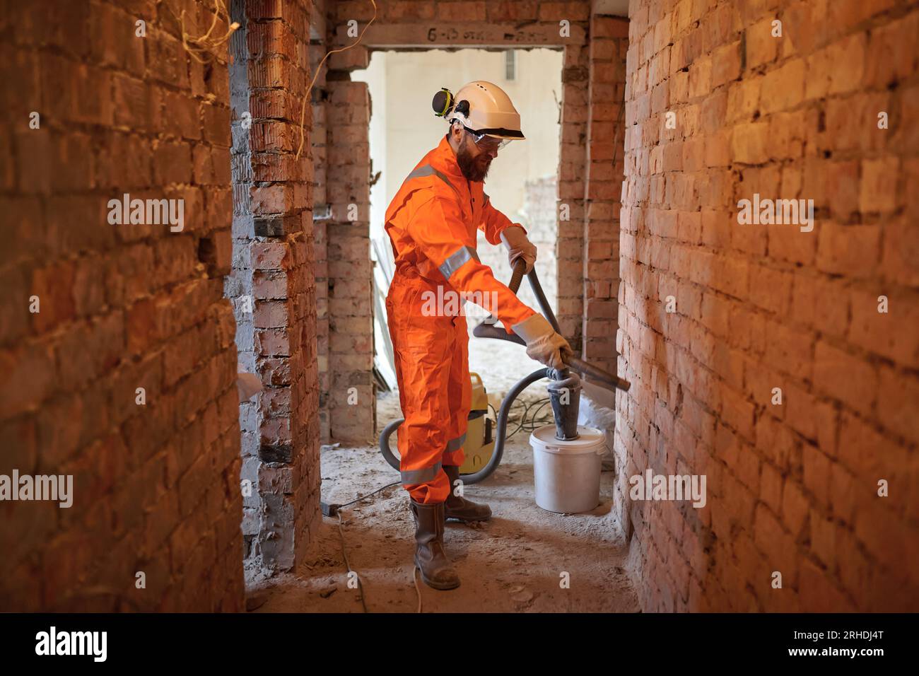 Constriction site worker cleaning brick wall with special vacuum cleaner. Stock Photo