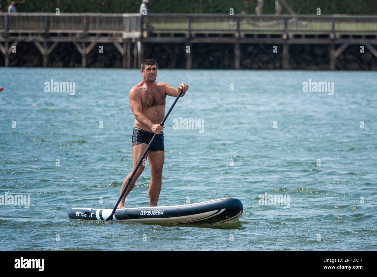 Boy on the beach on a Paddle Surf in the water. Stock Photo