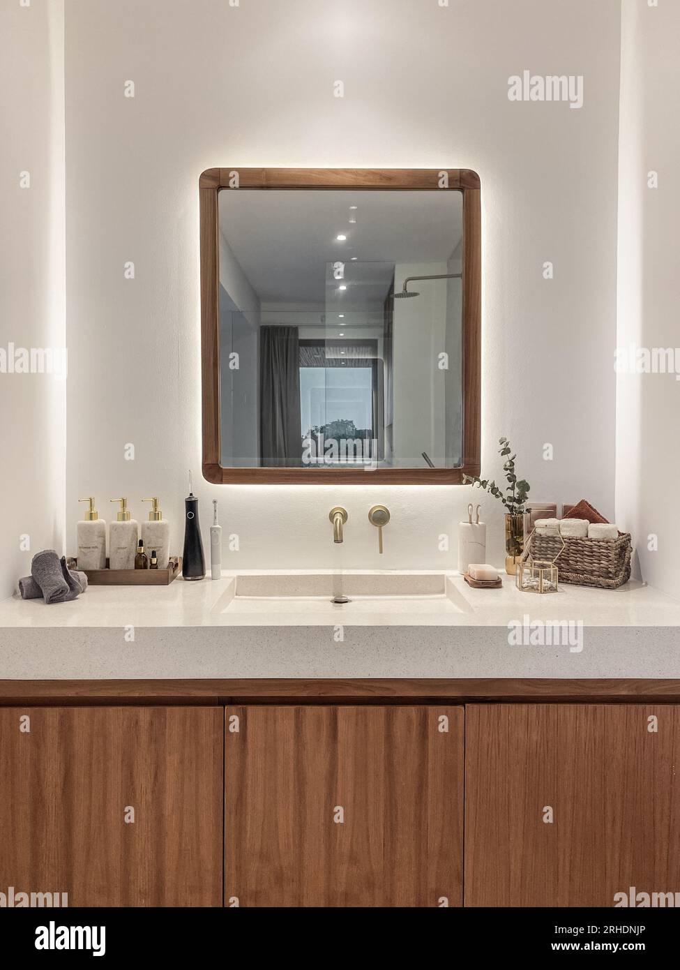 https://c8.alamy.com/comp/2RHDNJP/golden-modern-mixer-tap-in-the-bathroom-with-stone-liquid-soap-dispenser-tooth-brushes-wicker-basket-with-towels-and-mirror-in-bathroom-2RHDNJP.jpg