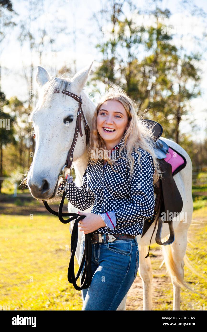 Happy young adult person laughing with her horse in Aussie sunlight Stock Photo