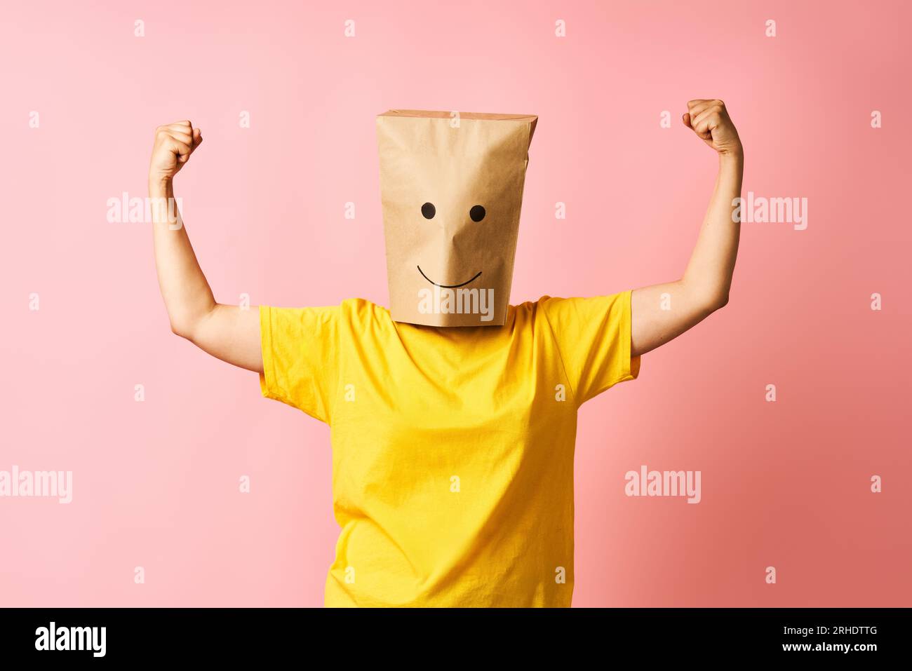 Happy woman with paper bag over head show biceps muscles proud of achievements and personal success. Girl power concept Stock Photo
