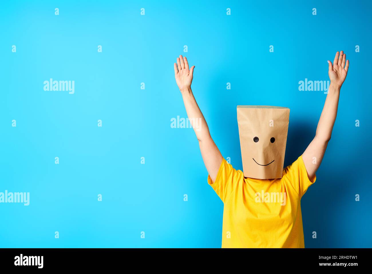 Woman with happy smile on the paper bag on head celebrating success with winner gesture. Copy space. victory, triumph and emotions concept Stock Photo