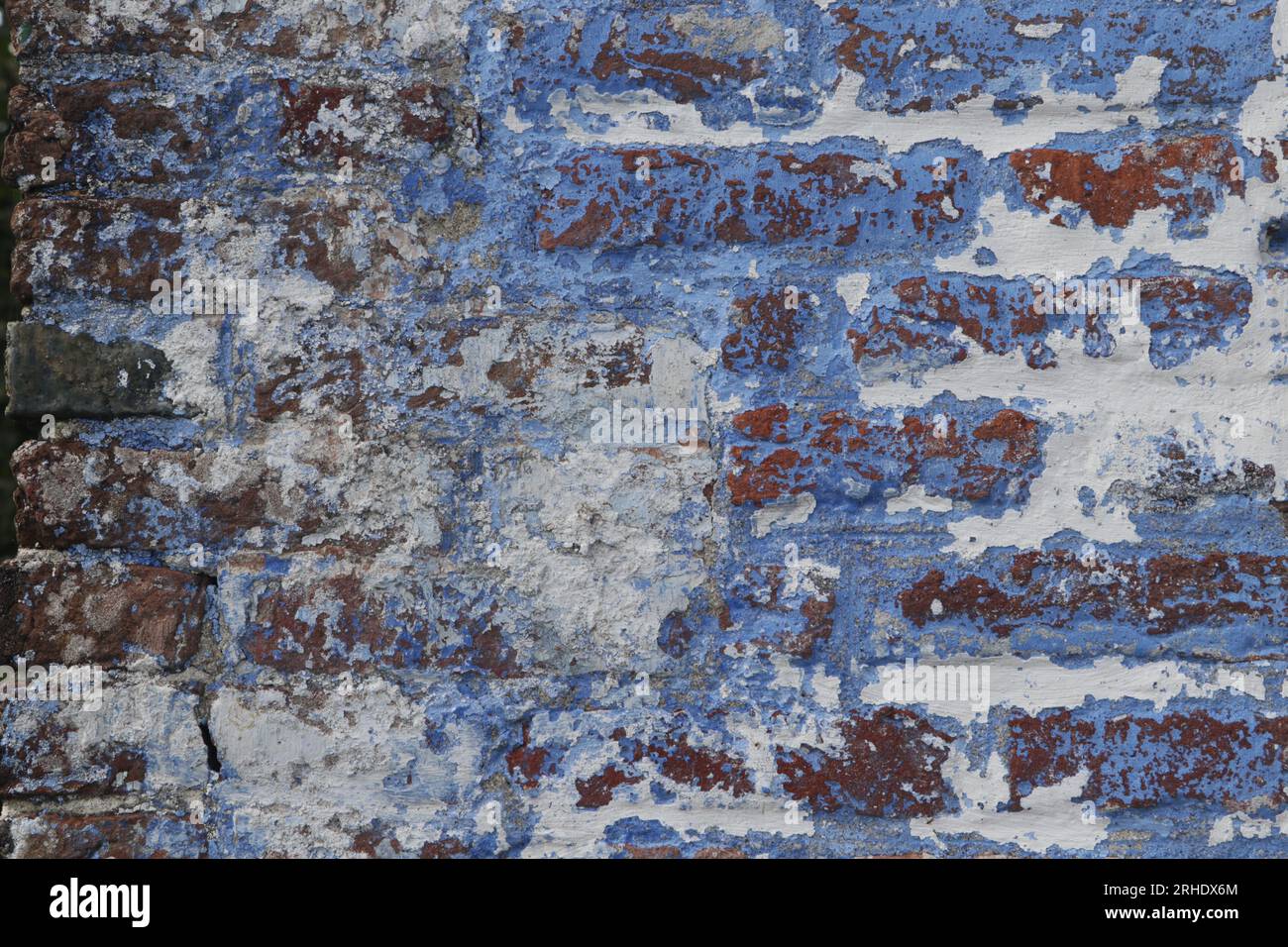 detail of old brick wall with peeled off blue and white paint Stock Photo
