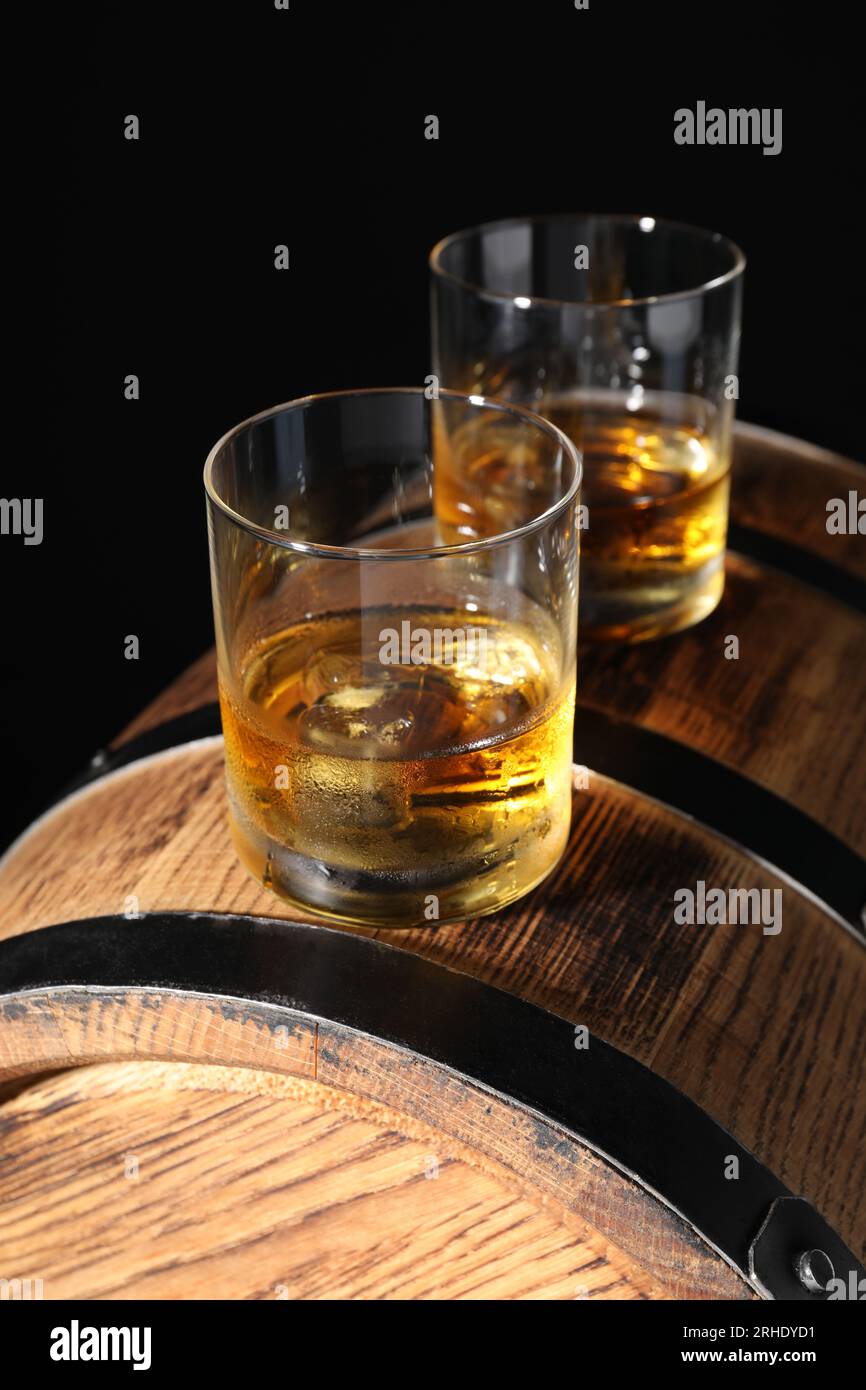 Glasses of tasty whiskey on wooden barrel Stock Photo