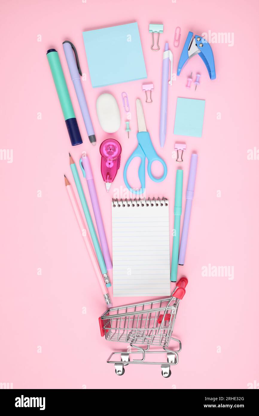 School and office supplies with shopping cart on pink background, mock-up top view, shopping concept close-up Stock Photo