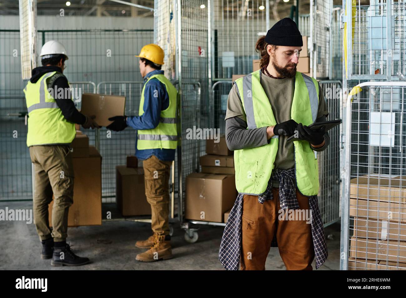 Young serious male engineer in reflective jacket looking at tablet screen while networking or looking through information in database Stock Photo
