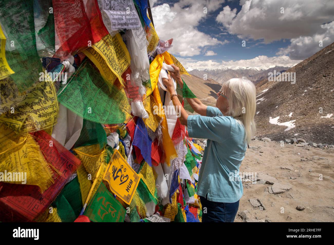 India, Ladakh, Khardung La, tourist tying prayer flag at top of 5620m
