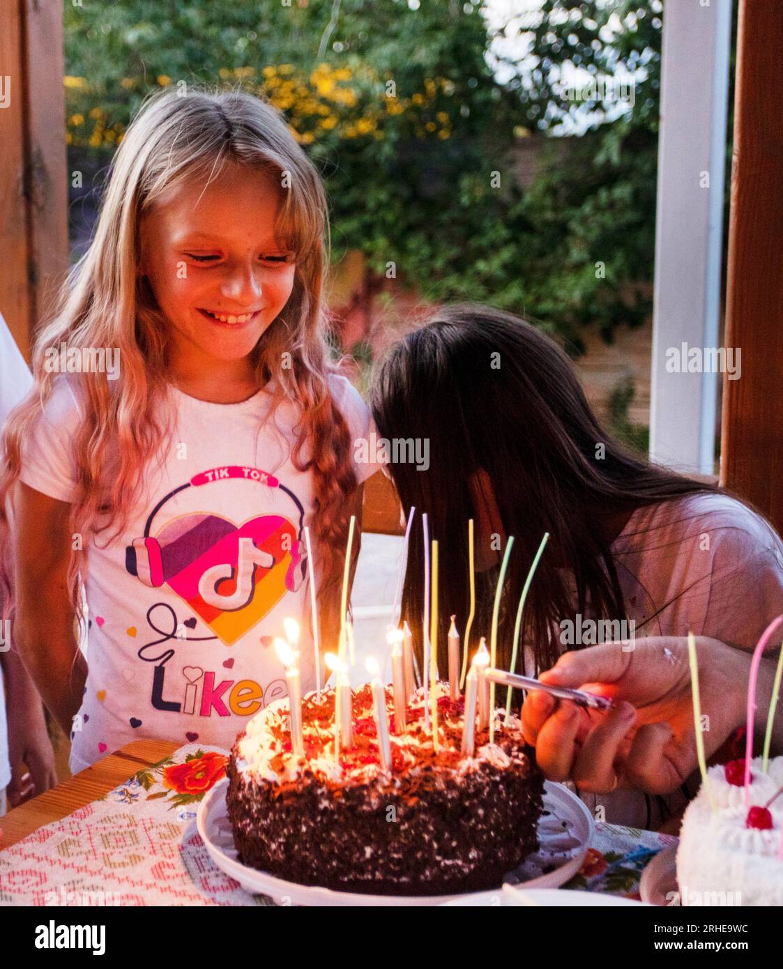 Happy Girl Blows Out Festive Candles On Her Birthday Cake Stock Photo happy-girl-blows-out-festive-candles-on-her-birthday-cake-stock-photo