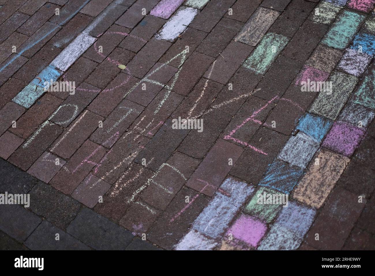 Save The Planet, graffitied in Chalk, a handwritten  message on the brick pavement in rainbow colours, bricks coloured in pink, blue, yellow, white Stock Photo