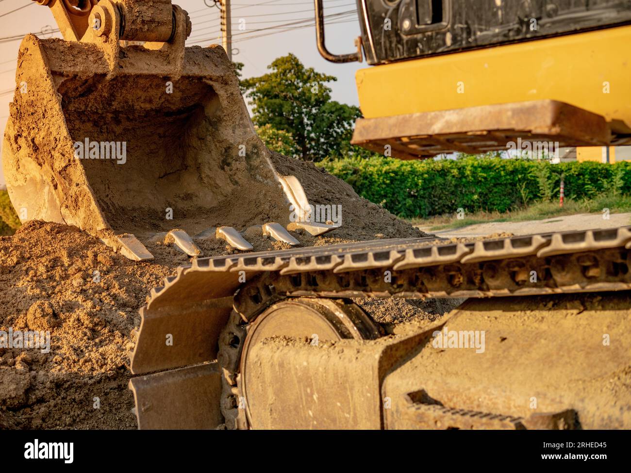 Backhoe parked at construction site after digging soil. Closeup bucket of bulldozer. Digger after work. Earth moving machine at construction site Stock Photo