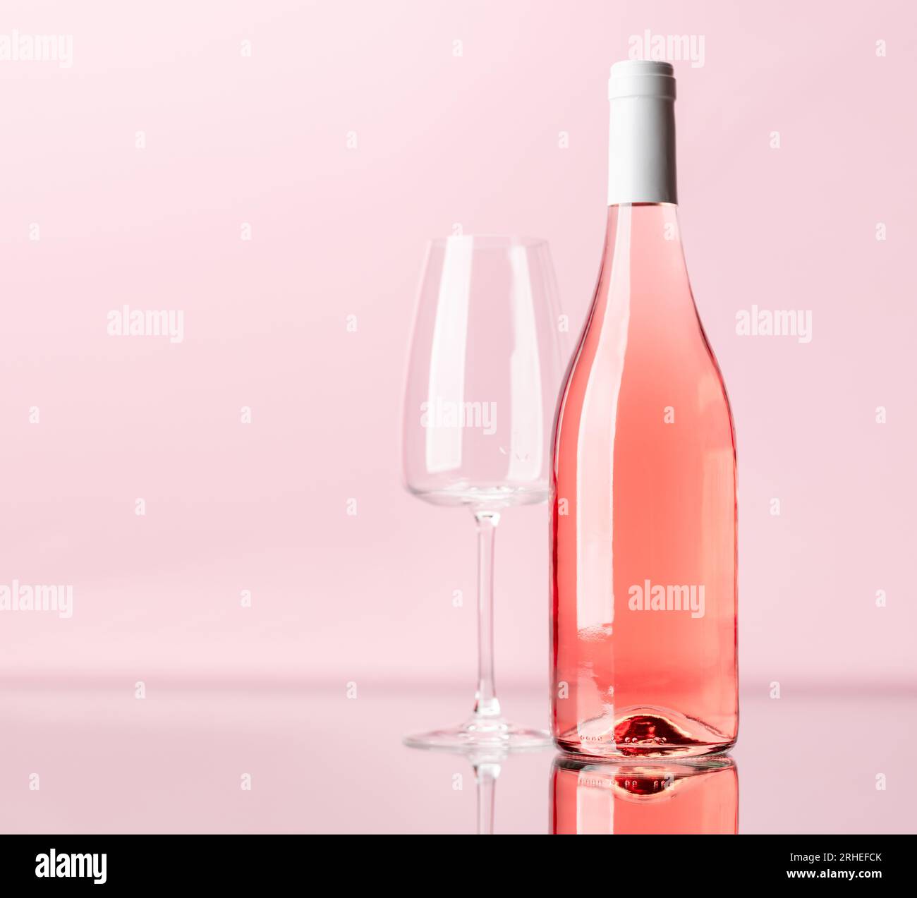 Rose wine bottle and wine glass over rose background. With copy space