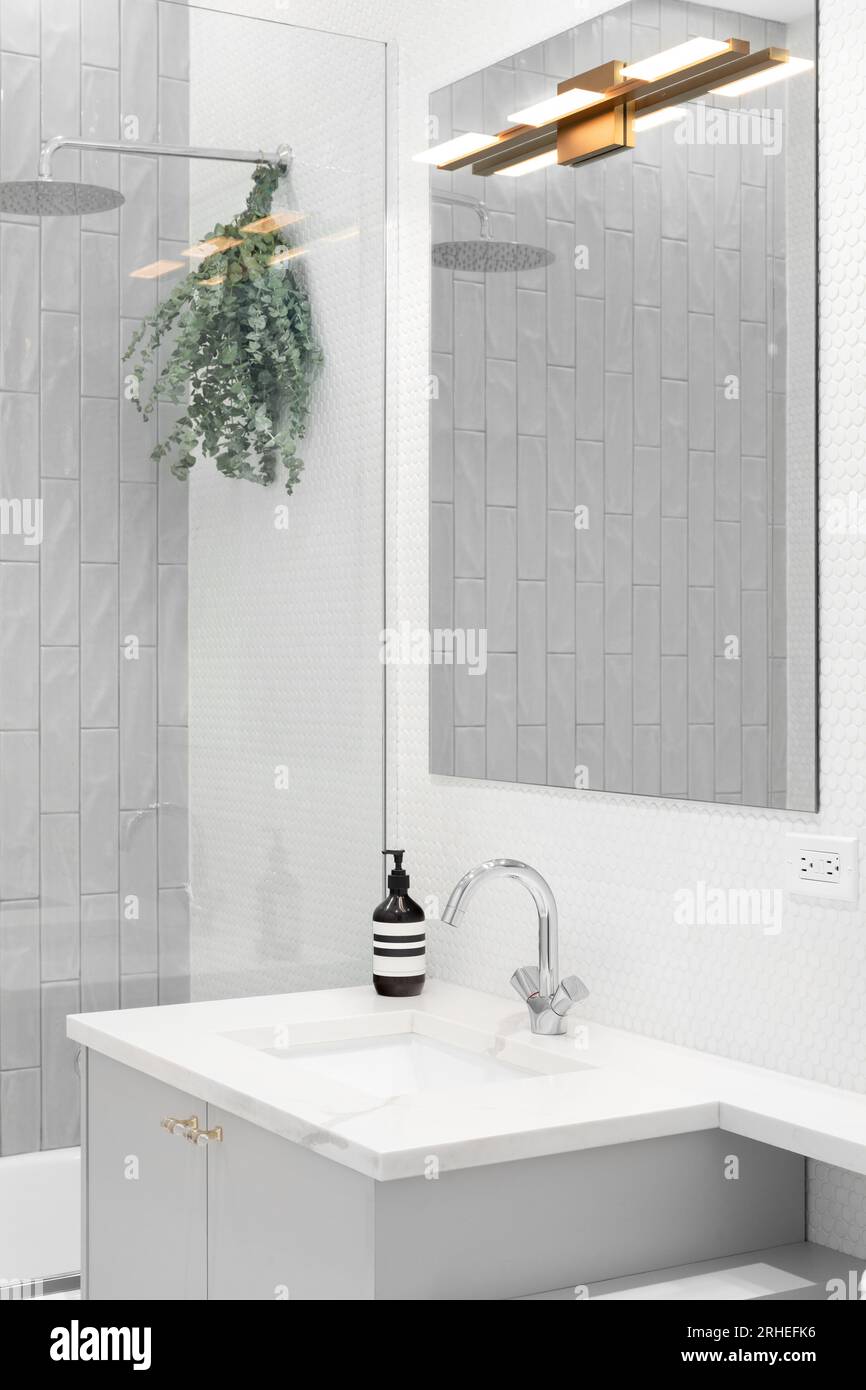 A bathroom detail with a grey vanity gold light fixture