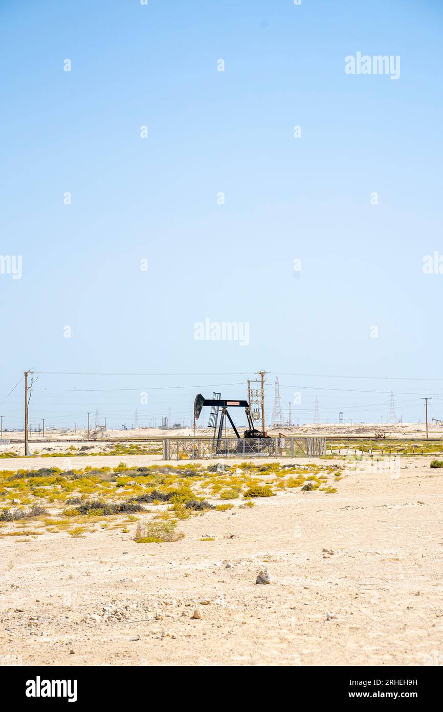 Bahrain oil field infrastructure -  pump jack,oil horse, oil jack, beam pump extracting crude oil from oil well in the Bahrain desert Stock Photo