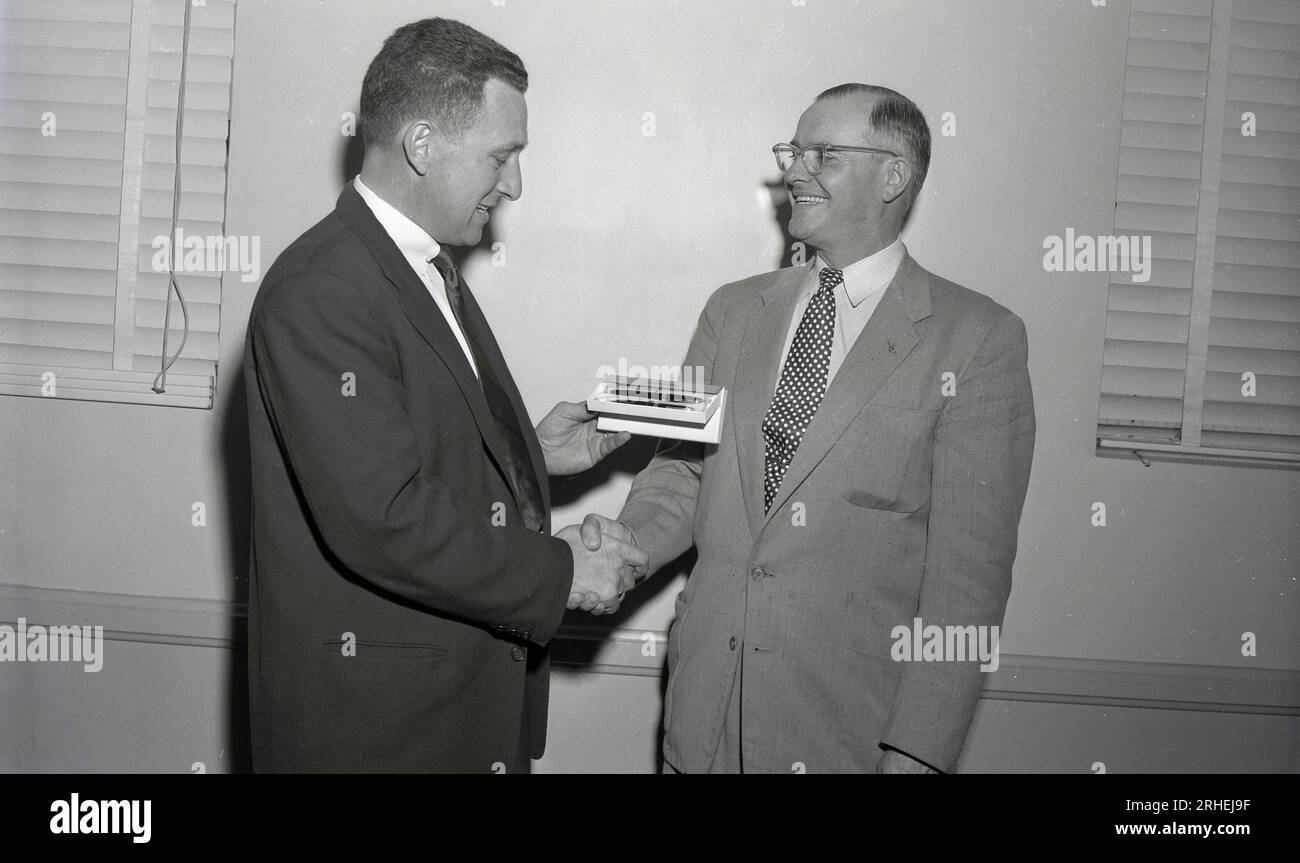 1950s, historical, business gift....a handshake as a suited gentleman is presented with a Sheaffers ink pen & pencil set by another man, USA. The Sheaffer pen company is over 100 years old dating back to its formation in 1913. Stock Photo