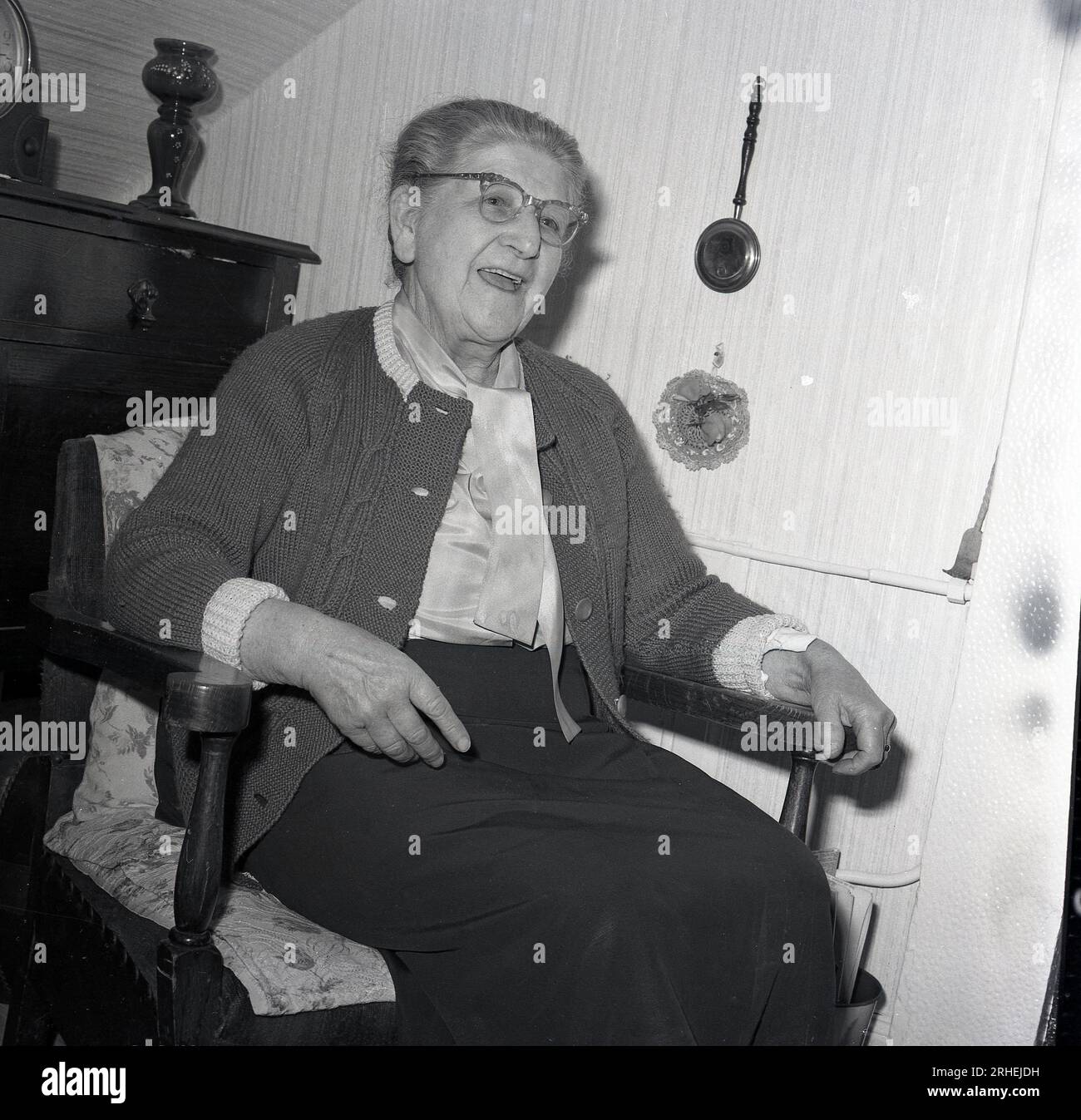 1965, historical, sprightly elderly lady sitting in a wooden chair in an old peoples home, England, UK. Stock Photo