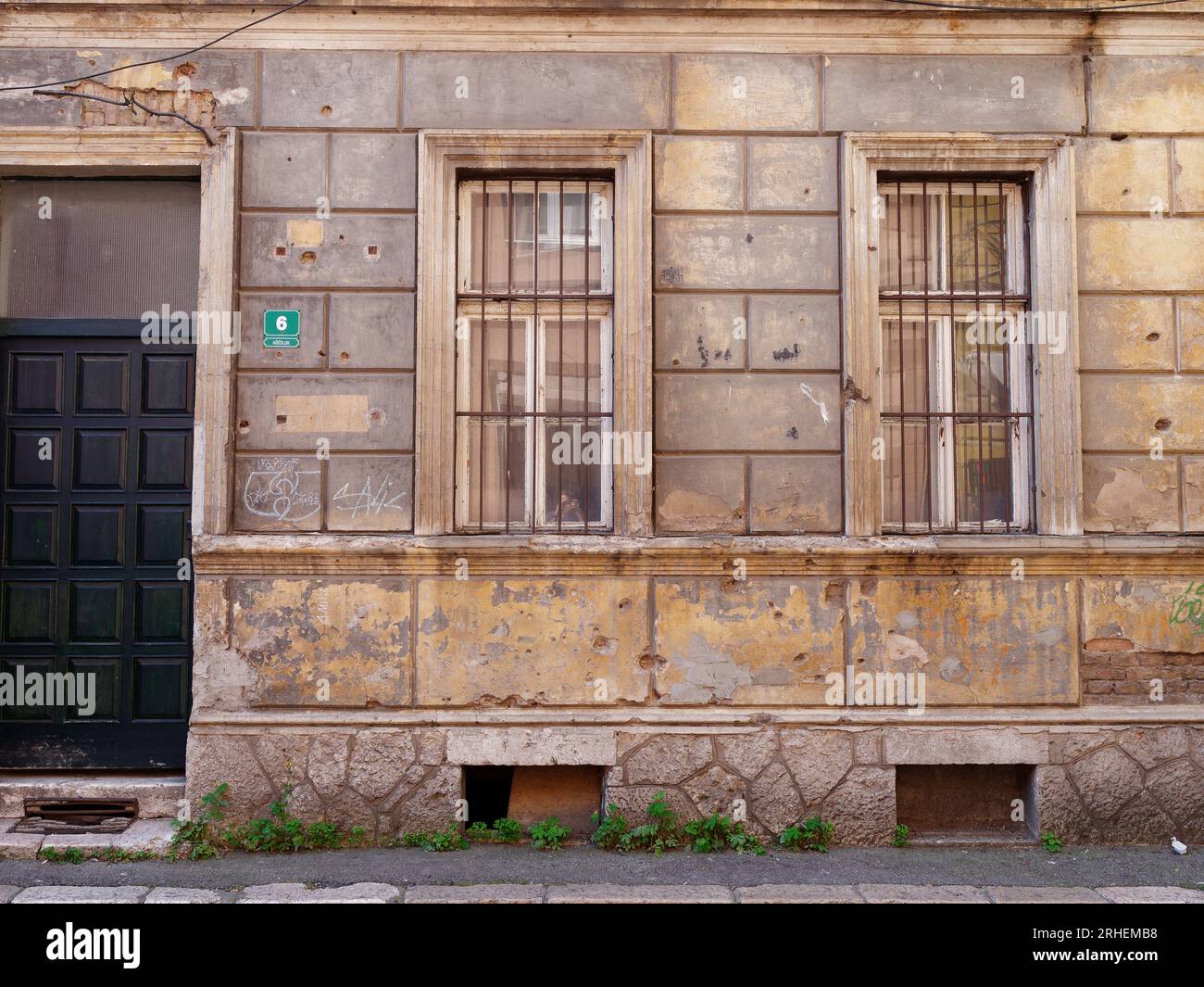 Shell, shrapnel and bullet holes in the side of a building with metal window grills, city of Sarajevo, Bosnia and Herzegovina, August 16,2023. Stock Photo