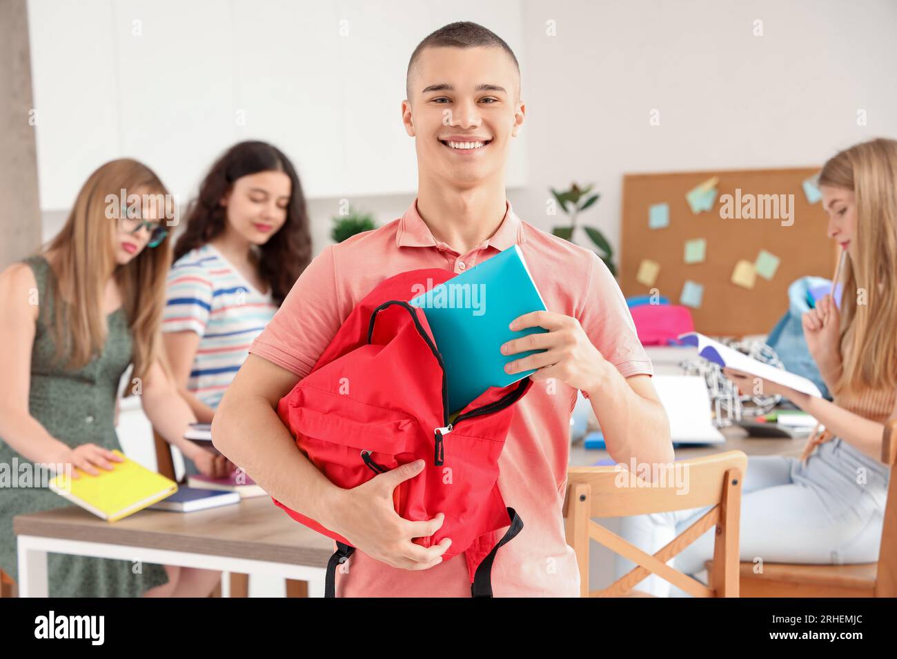 Male student taking copybook out of backpack in kitchen Stock Photo