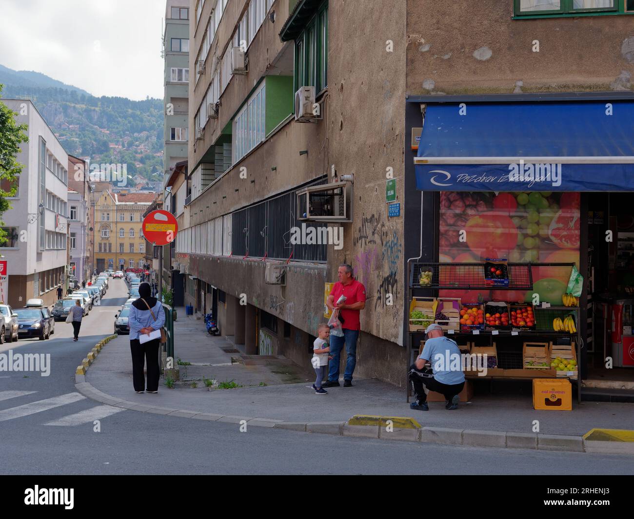 People outside a fruit and vegetable store with cars parked along the street in the city of Sarajevo, Bosnia and Herzegovina, August 16,2023. Stock Photo