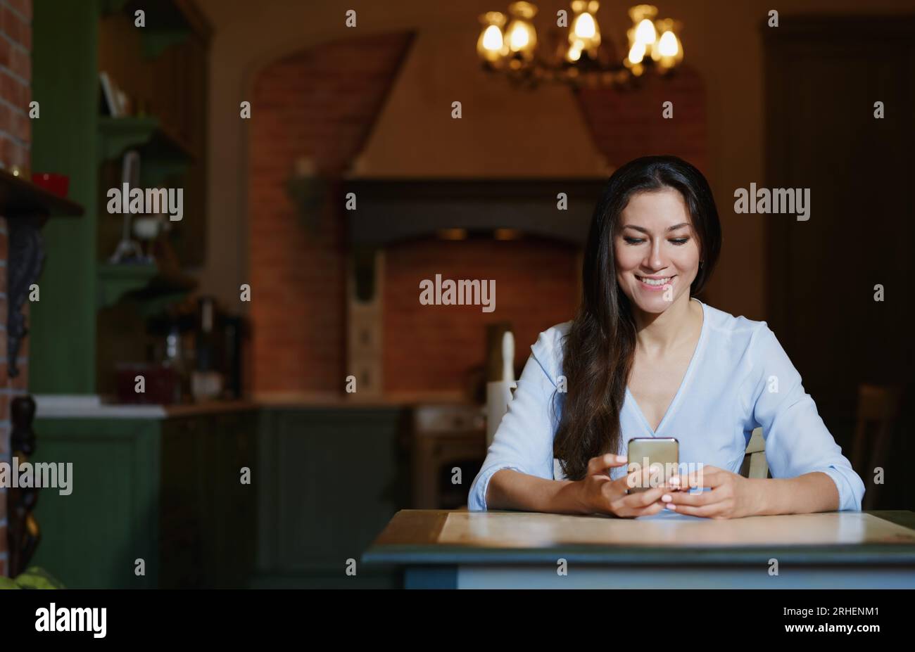 Smiling woman sitting and table and using smartphone Stock Photo