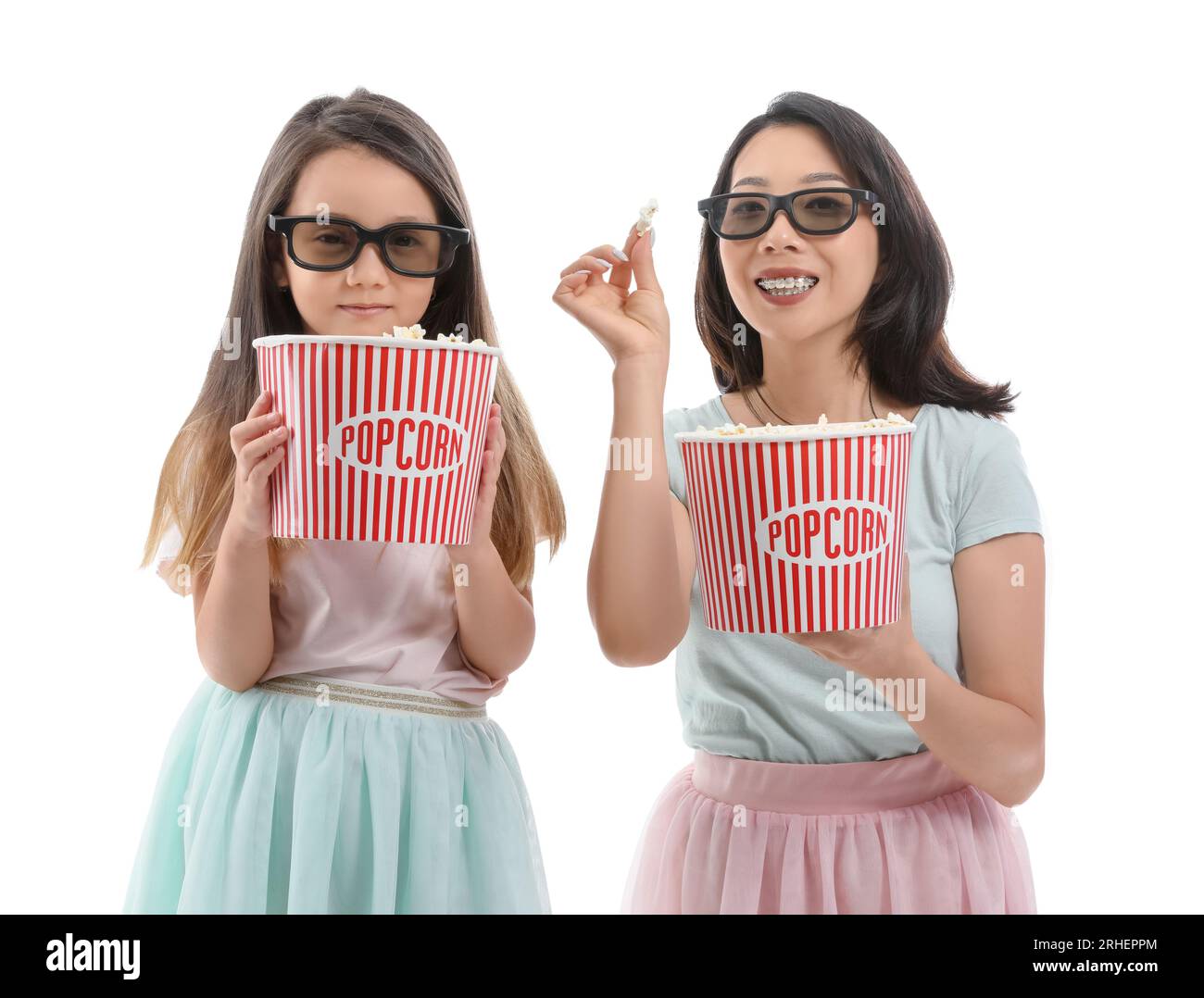 Asian mother with her little daughter in 3D glasses eating popcorn on white background Stock Photo