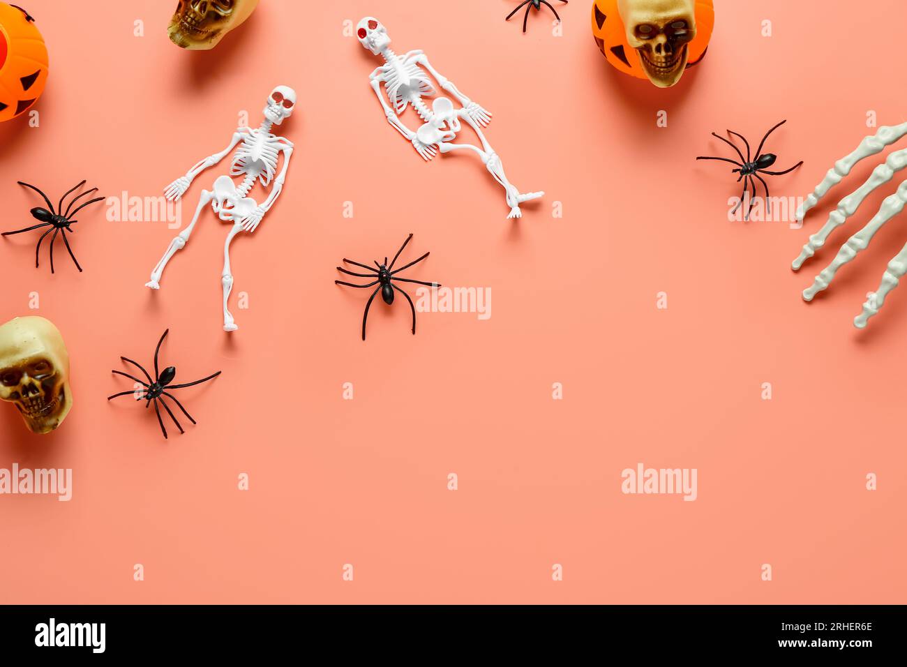 Composition with skeletons, hand, skulls, pumpkins and spiders for Halloween celebration on coral background Stock Photo