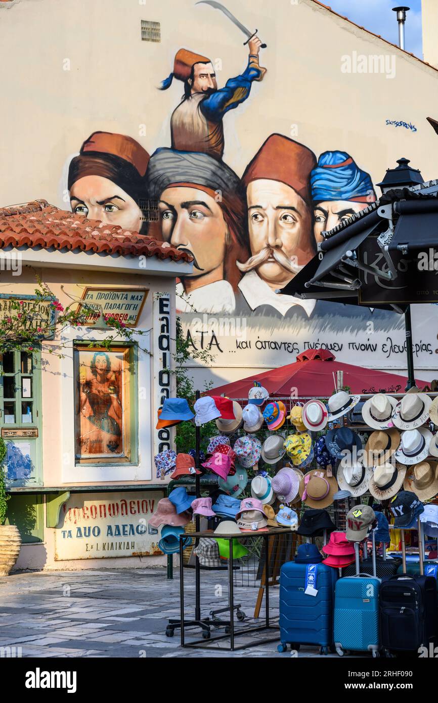 A hat shop with a mural in the backround of Greek heroes of the war of independence.  In the bazaar district in the old quarter of Kalamata, Messinia, Stock Photo
