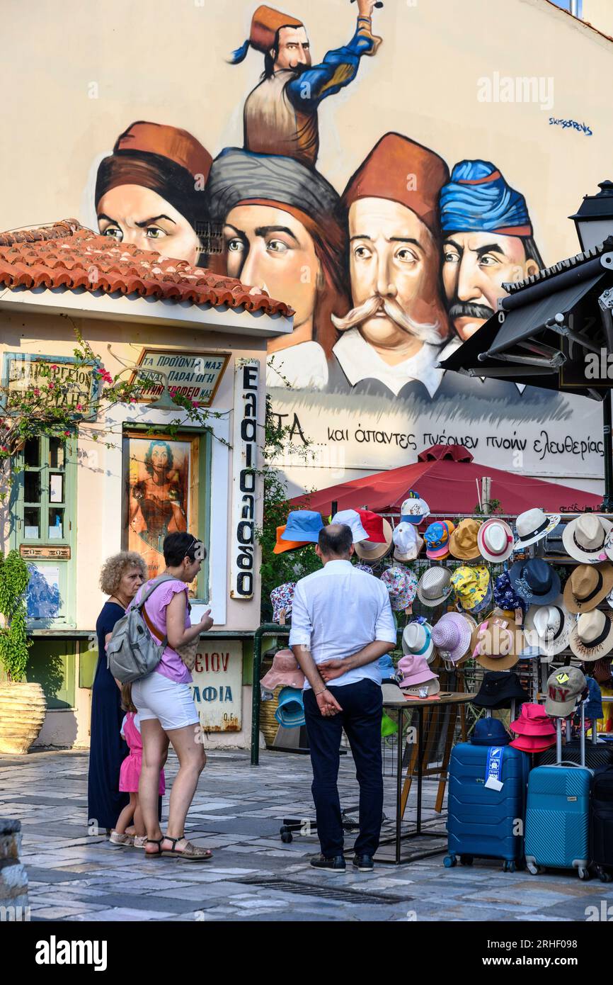 A hat shop with a mural in the backround of Greek heroes of the war of independence.  In the bazaar district in the old quarter of Kalamata, Messinia, Stock Photo