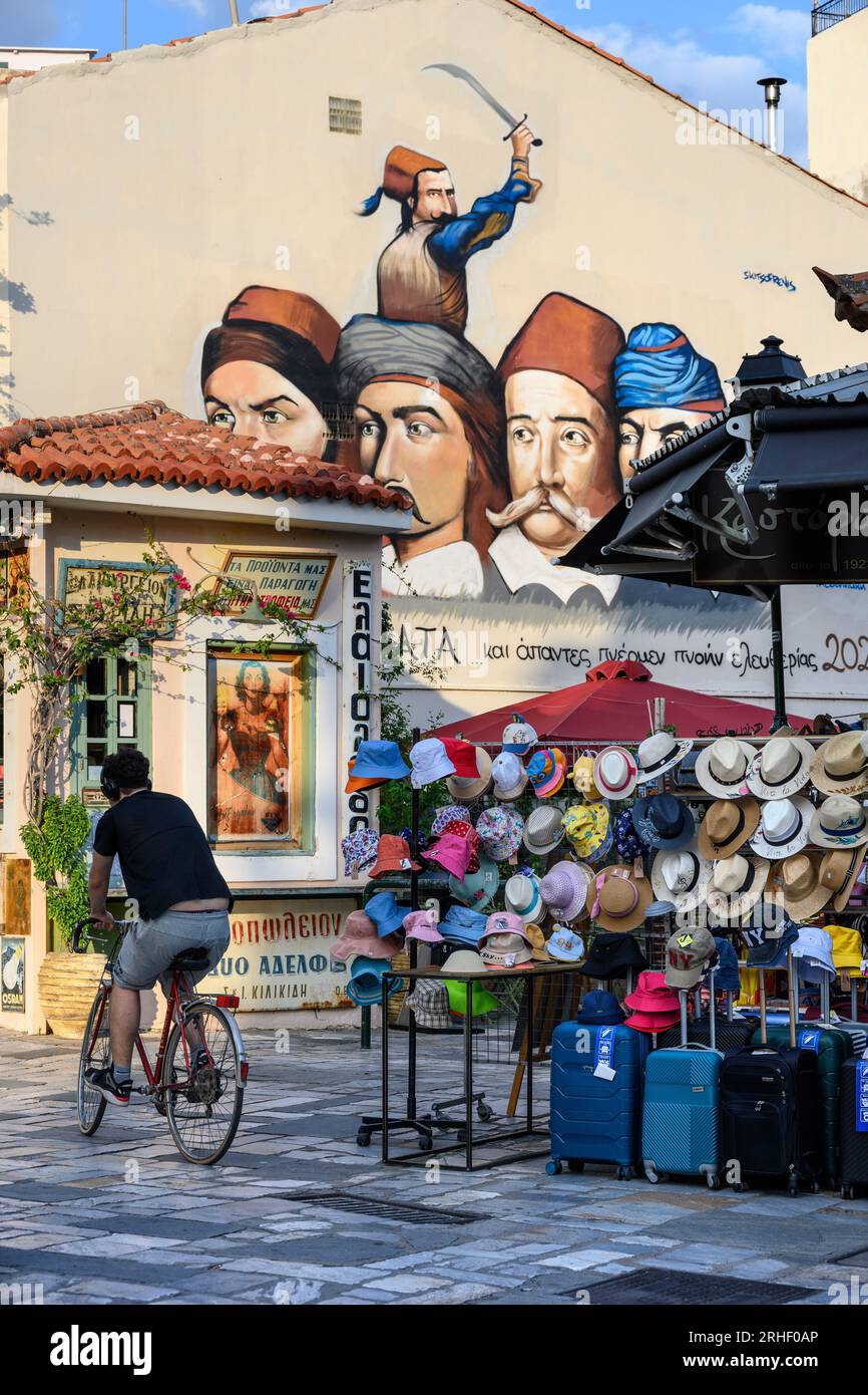 A hat shop with a mural in the backround of Greek heroes of the war of independence.  In the bazaar district in the old quarter of Kalamata, Messinia, Stock Photo