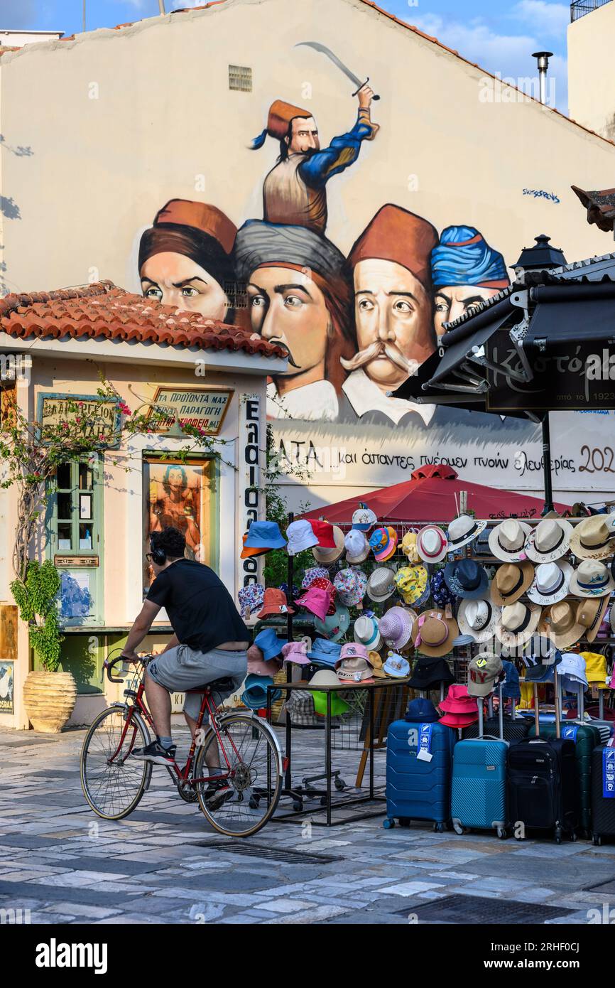 A hat shop with a mural in the backround of Greek heroes of the war of independence.  In the bazaar district in the old quarter of Kalamata, Messinia, Stock Photo