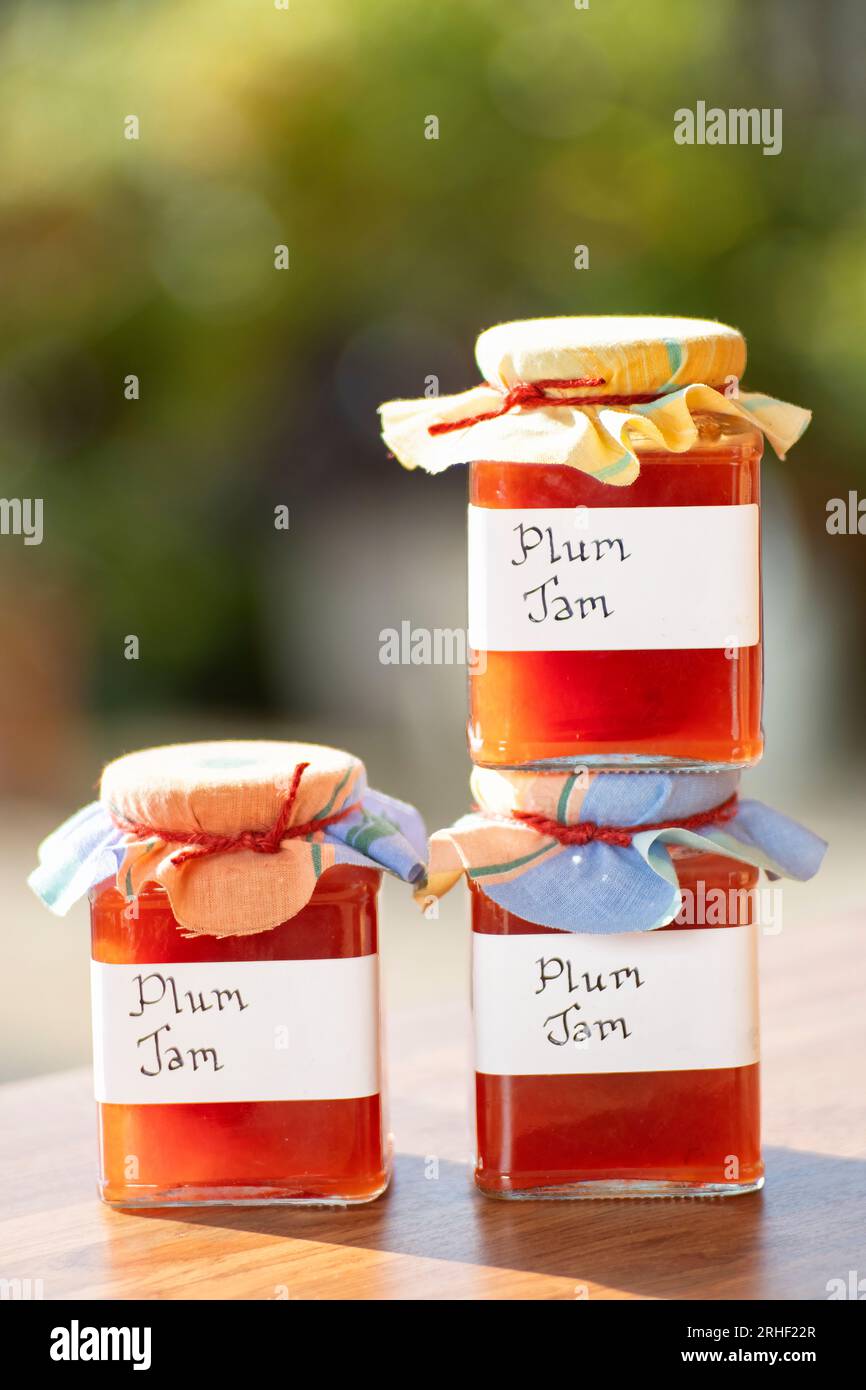 Jars of homemade plum jam. The glass jars have clear handwritten labels