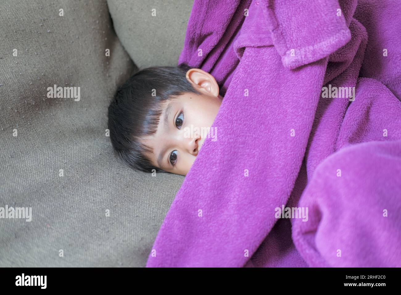 Sick child, child lying in bed, fully blanketed, having fever and sickness, health care Stock Photo