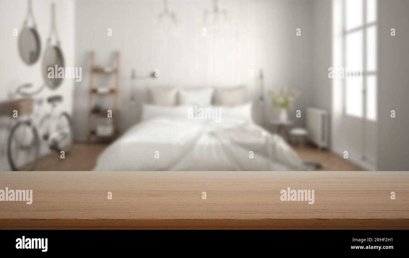 Empty wooden table, desk or shelf with blurred view of scandinavian white bedroom, bed with pillows, bicycle, decors and mirror, modern interior desig Stock Photo