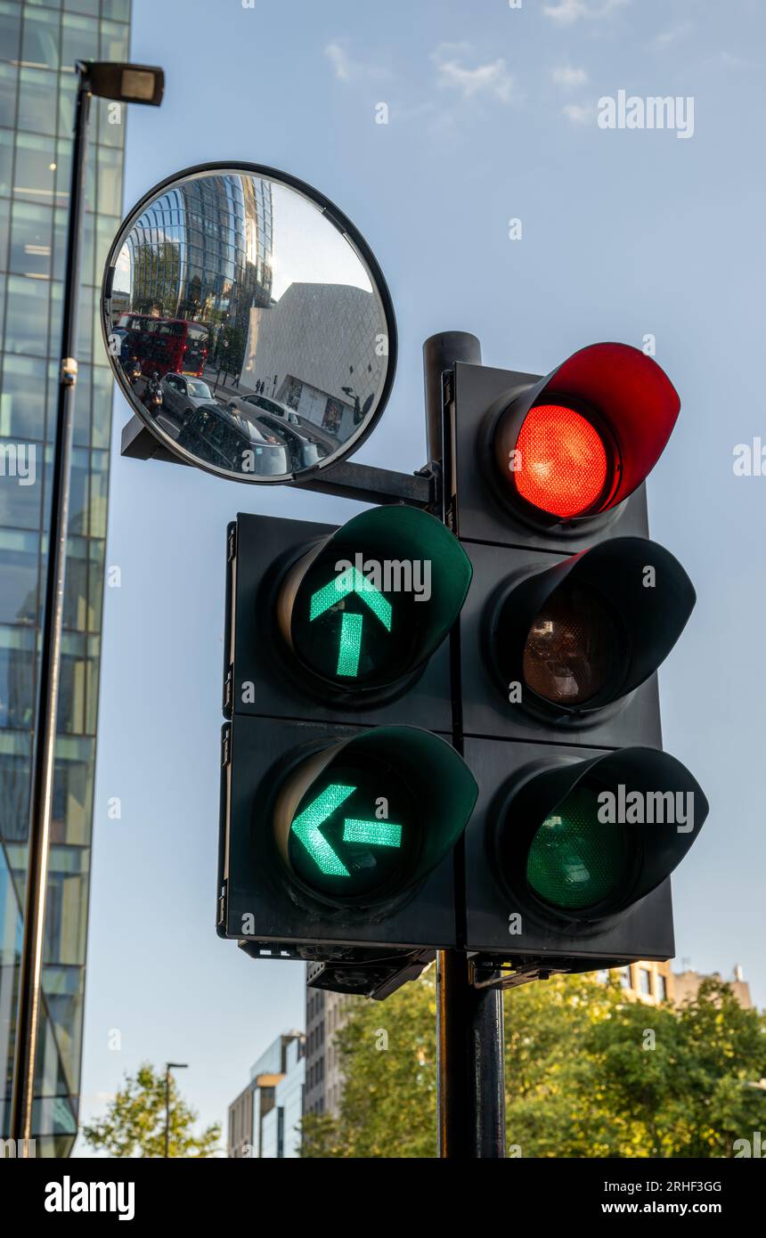 London, UK: Red traffic light with green filter lights in London. Stop light with mirror reflecting the waiting traffic. Stock Photo