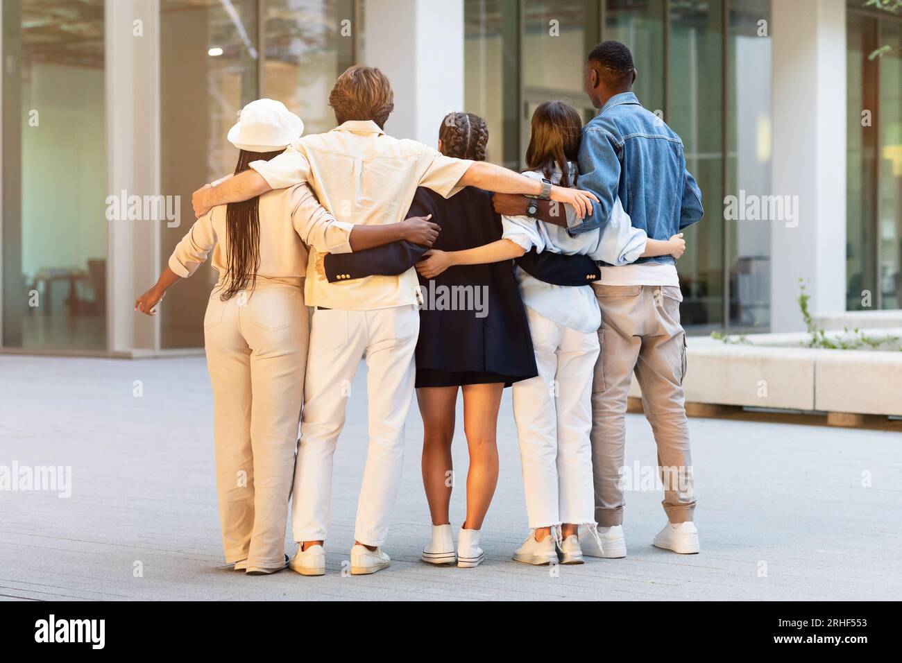 Back view of multiethnic friends embracing on the street Stock Photo ...