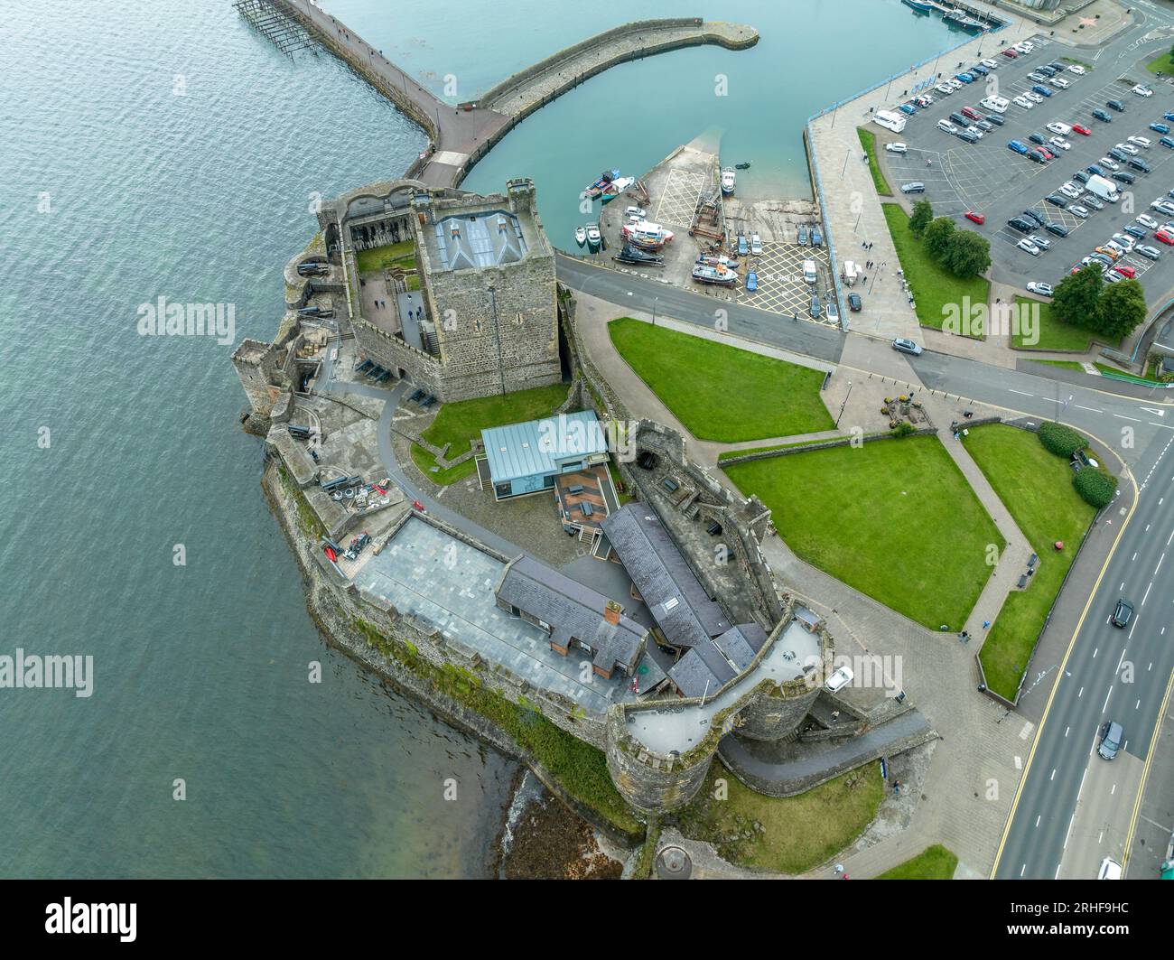 Aerial view of Carrickfergus Castle in Carrickfergus, Northern Ireland, jutting out into Belfast Lough, surrounded by water and the town.