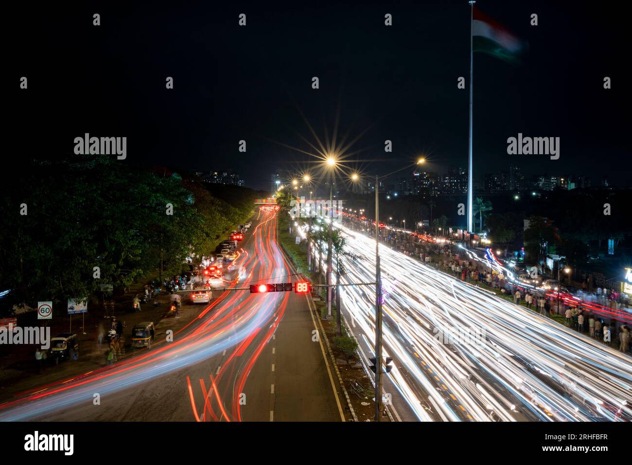 Navi Mumbai, India- August 15 2023 Vehicle light trails at night on palm beach road in Navi Mumbai, India with Indian flag in background Stock Photo