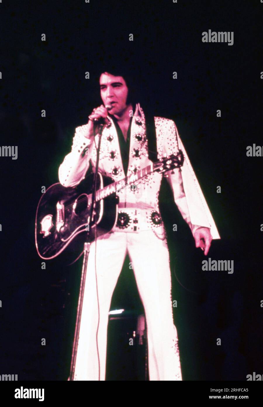 Elvis Presley wearing one of his iconic white embellished jumpsuits with  guitar, singing on stage, circa 1970's. Photo: Oscar Abolafia/Everett  Collection (elvispresley014 Stock Photo - Alamy, image size:900x1390